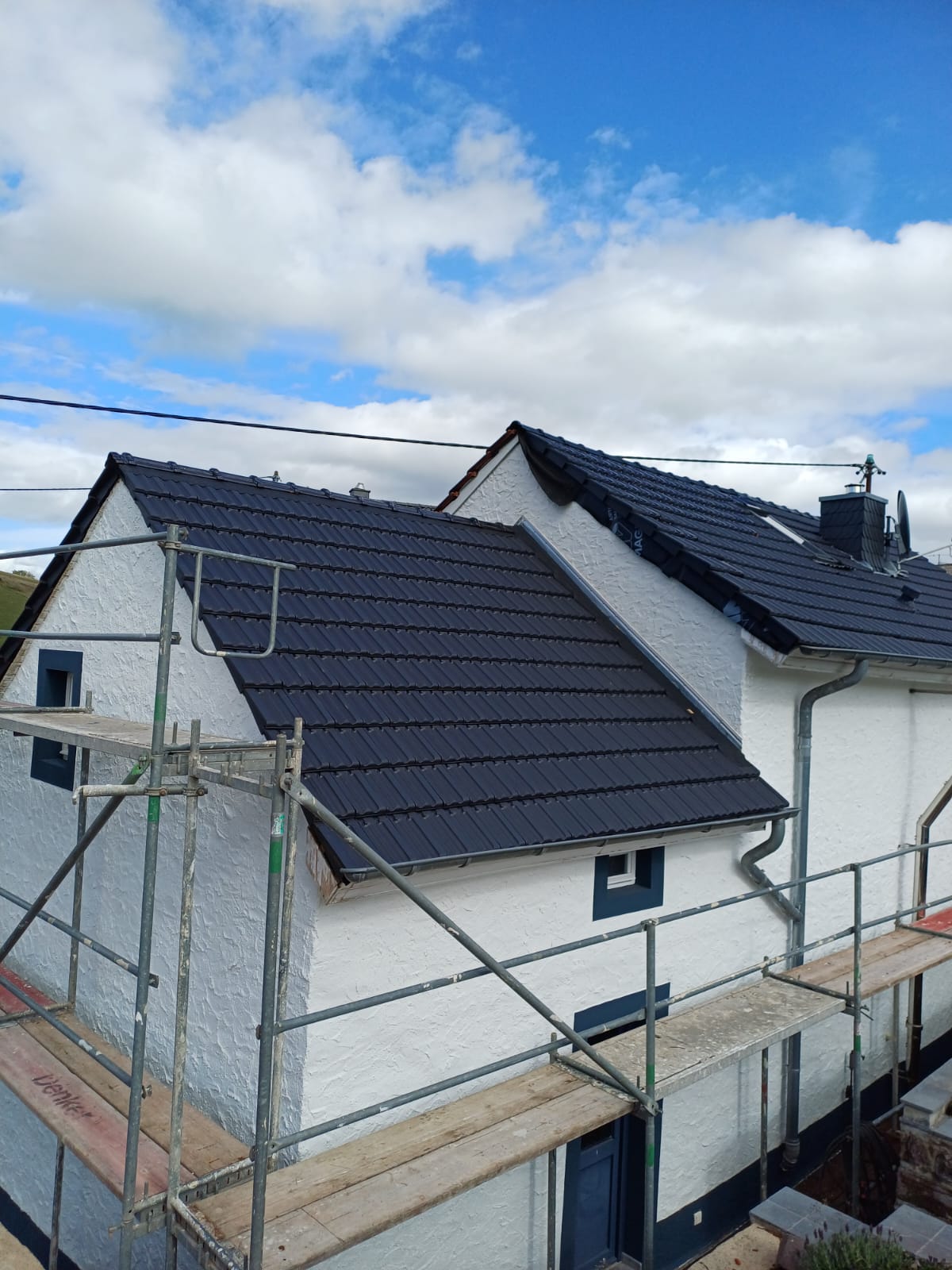 Neues Dach mit dunklen Ziegeln und Gerüst